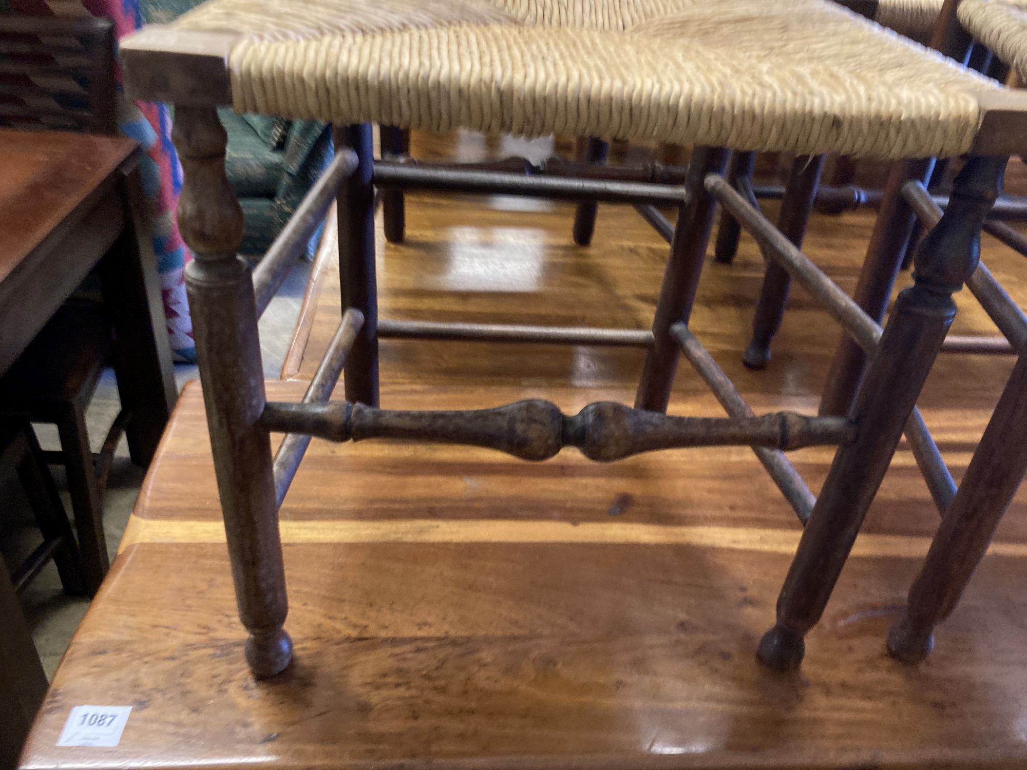 A set of four George III country oak rush seated chairs, with shaped back splat, turned supports and stretchers